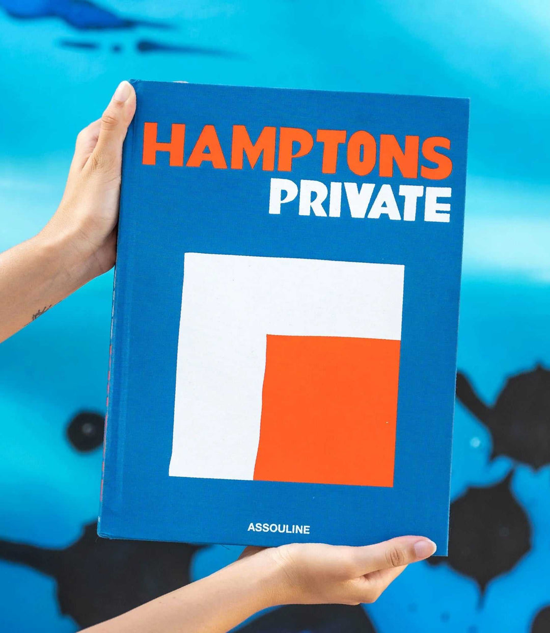 Hamptons Private coffee table book with blue cover and bold orange and white text, showcasing luxury Hamptons lifestyle.
