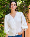 Woman wearing a white blouse with ruffled sleeves in a garden setting