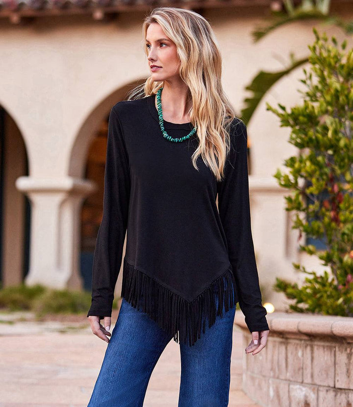 Woman wearing black asymmetric fringe top with long sleeves and crew neck paired with blue jeans outdoors