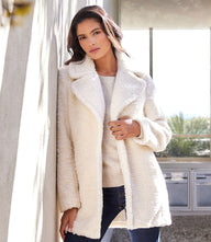 Woman wearing a cozy white plush Sherpa coat with long sleeves and notched collar outdoors