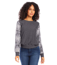 Woman wearing a dark gray sequin sleeve top with bishop sleeves and cuffed hem paired with jeans