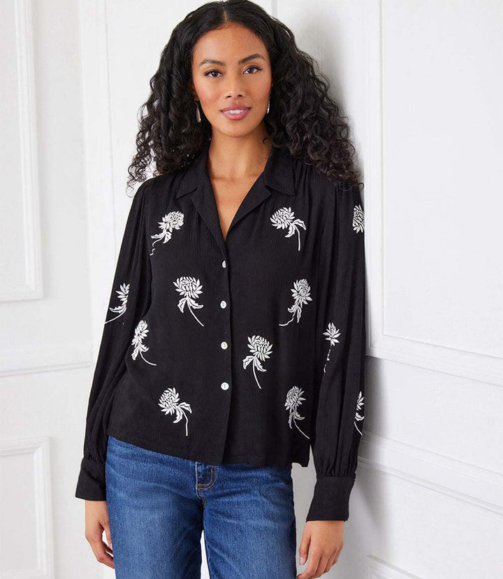 Black embroidered blouson sleeve top with pleated details and button front, made of lightweight rayon gauze.