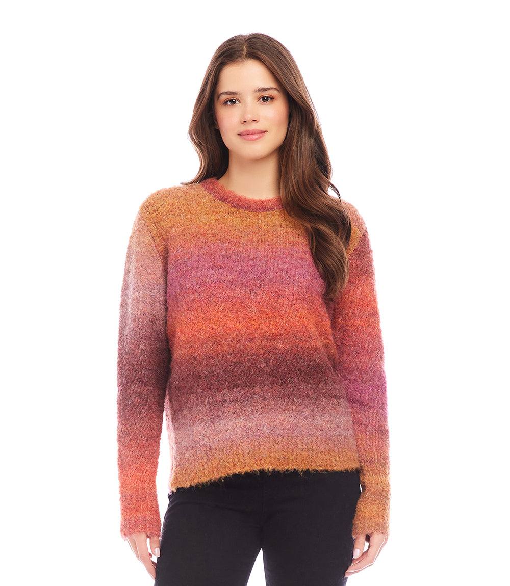 Woman wearing an ombre boucle sweater with a soft, loose fit and crew neck in shades of orange, pink, and purple.