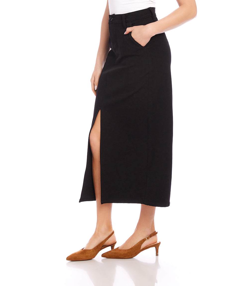 Chelsea Midi Skirt in black stretch twill with front slit, side pockets, and button closure, styled with brown slingback heels.