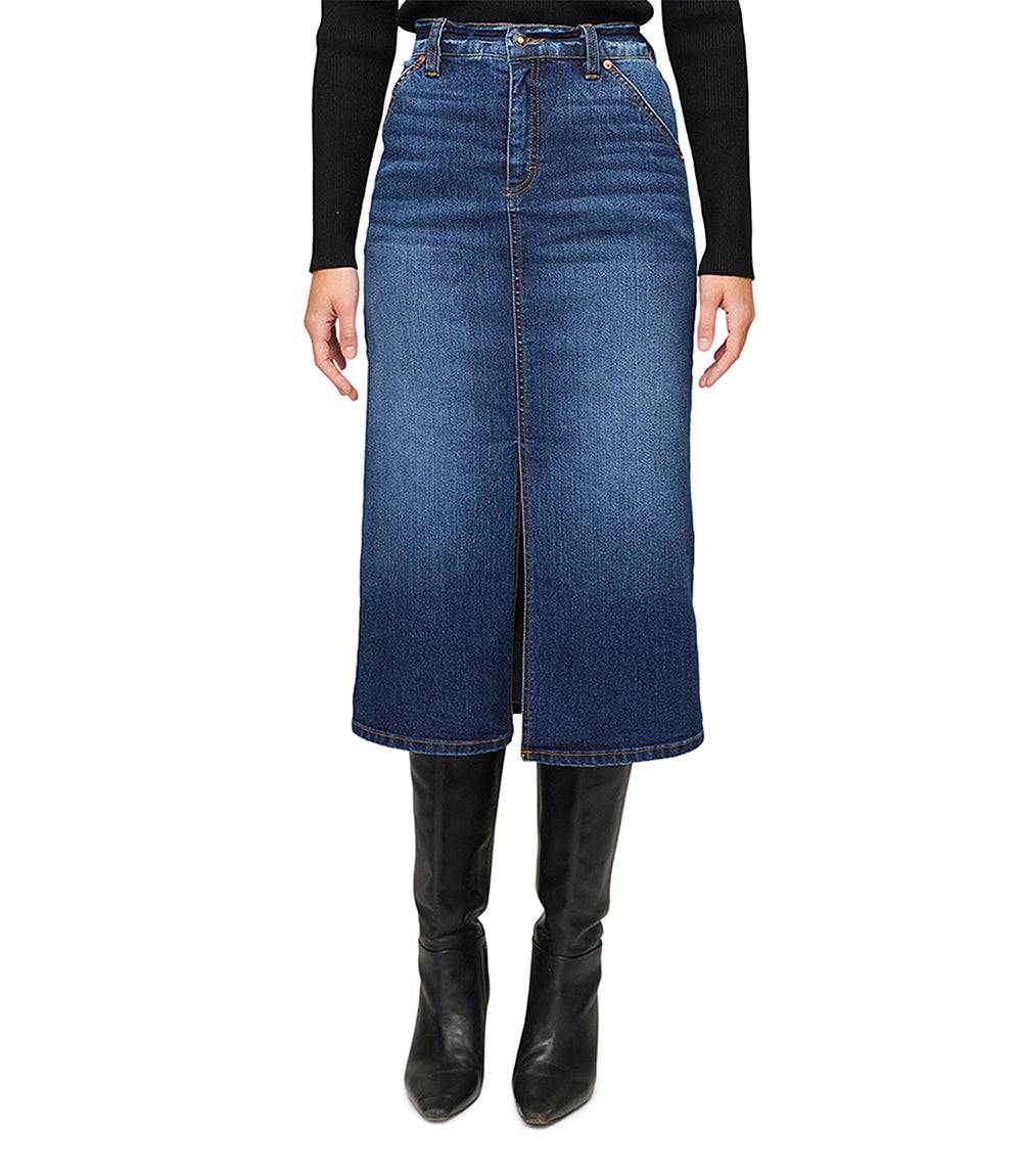 Women's blue denim midi skirt with front slit, zipper and button closure, styled with black long sleeve top and knee-high black boots