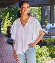 woman wearing white flutter sleeve top with button front and V-neck outdoors