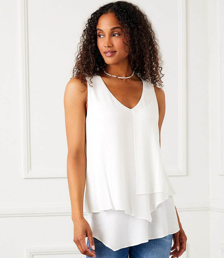Woman wearing white layered tank top with V-neckline and asymmetric layered hem