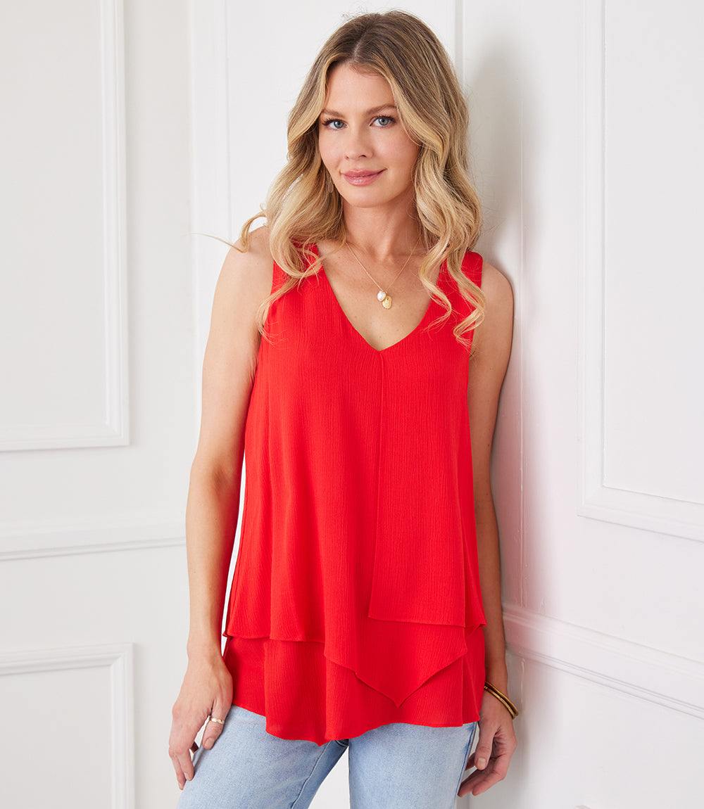 Red sleeveless layered tank top with V-neck and asymmetrical hem worn by woman