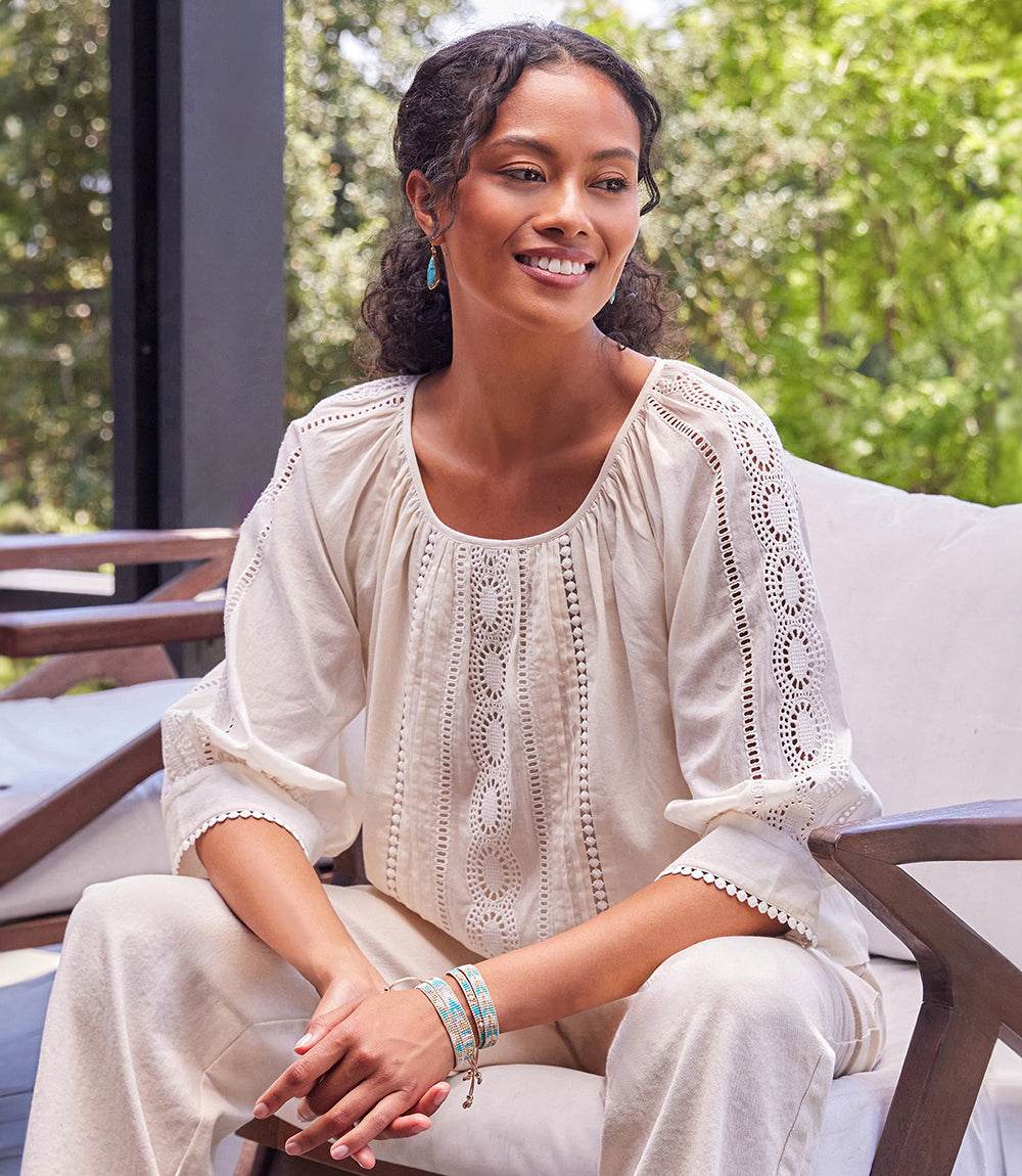 Woman wearing a relaxed fit Lace Inset Top with eyelet design and scoop neckline sitting outdoors
