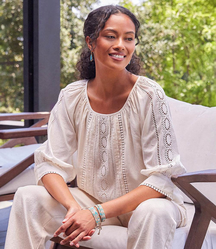 Woman wearing a relaxed fit Lace Inset Top with eyelet design and scoop neckline sitting outdoors