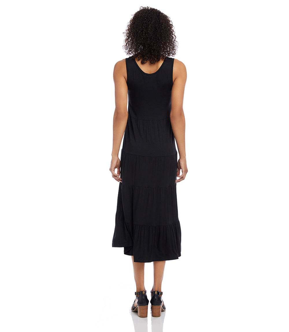 Black sleeveless tiered midi dress with scoop neckline and flouncy hem on model from back