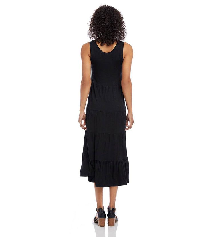 Black sleeveless tiered midi dress with scoop neckline and flouncy hem on model from back