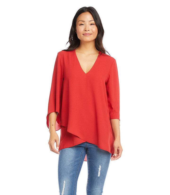 Woman wearing red Bracelet Sleeve Asymmetric Top with V-neck, flare sleeves, and layered asymmetrical hem paired with jeans.