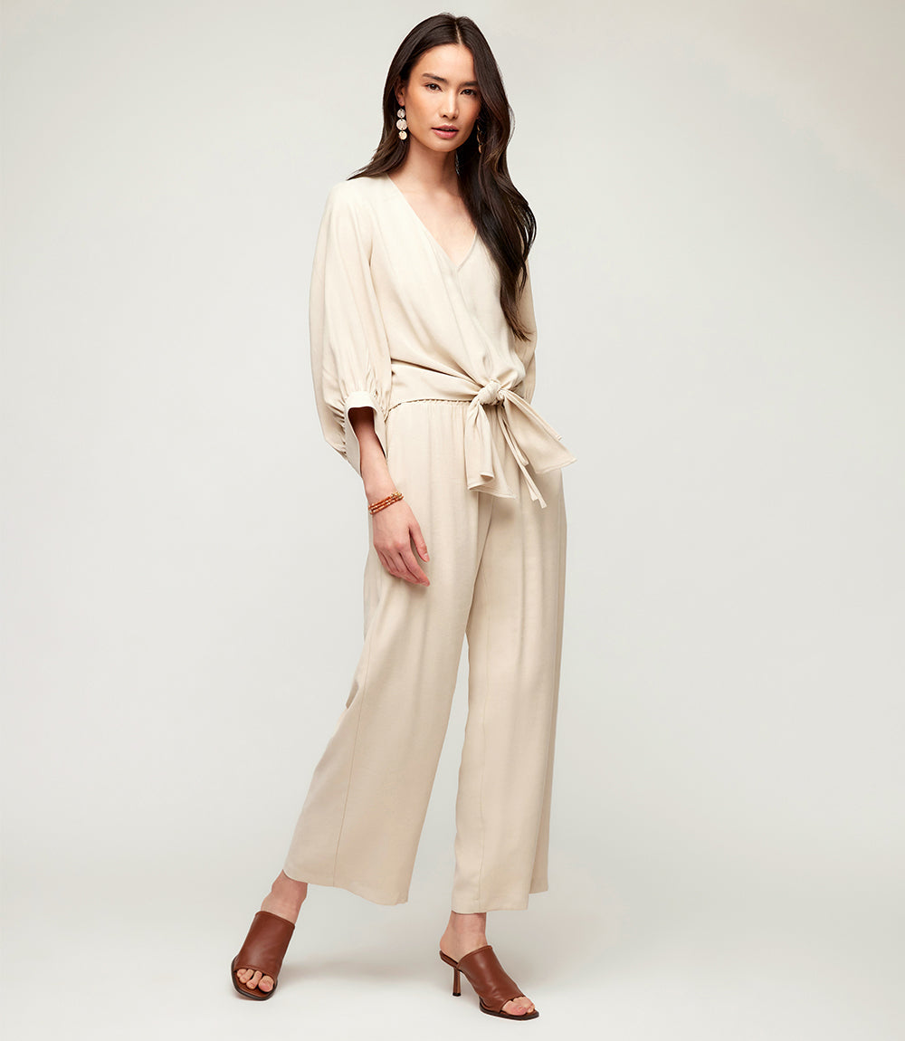 Woman wearing beige wide-leg drawstring pants with a matching top and brown heeled sandals