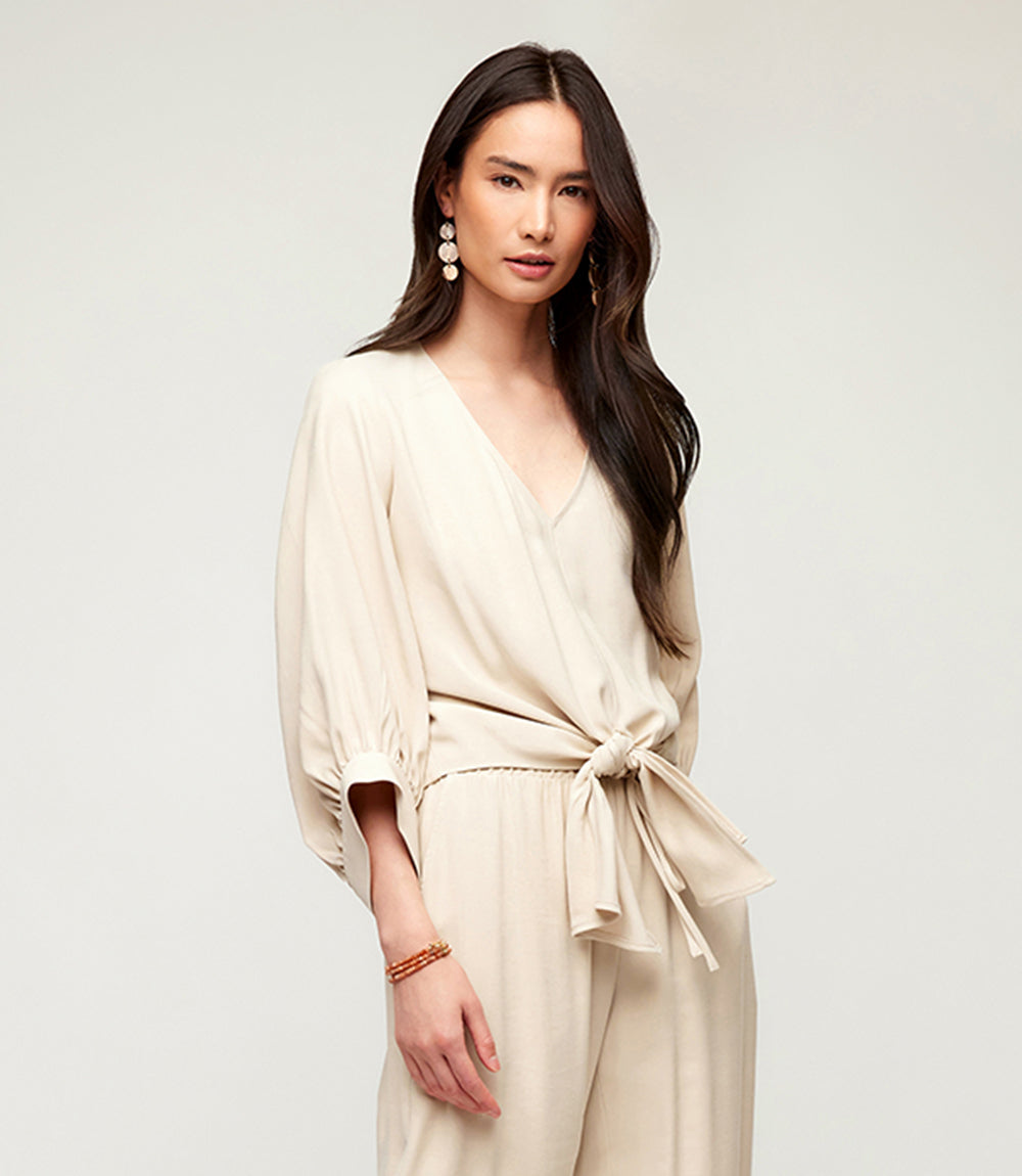 Woman wearing a cream Blouson Sleeve Tie-Front Top with V-neck and relaxed fit, styled with long flowing hair and statement earrings