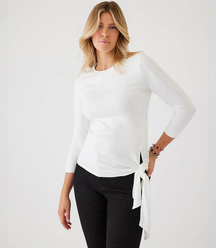 Woman wearing white three quarter sleeve side-tie top with crewneck and black pants