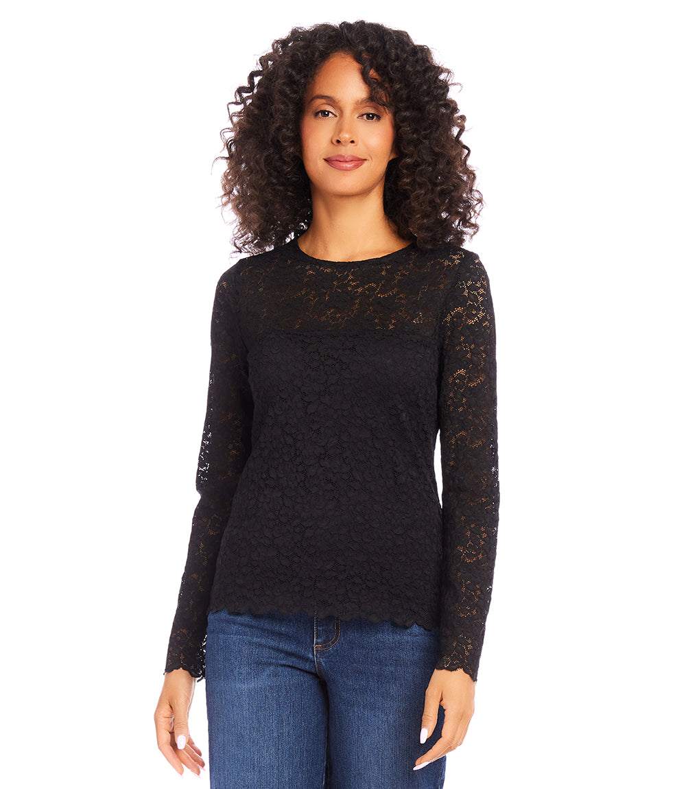 Woman wearing black scalloped lace top with sheer long sleeves and crew neck paired with blue jeans