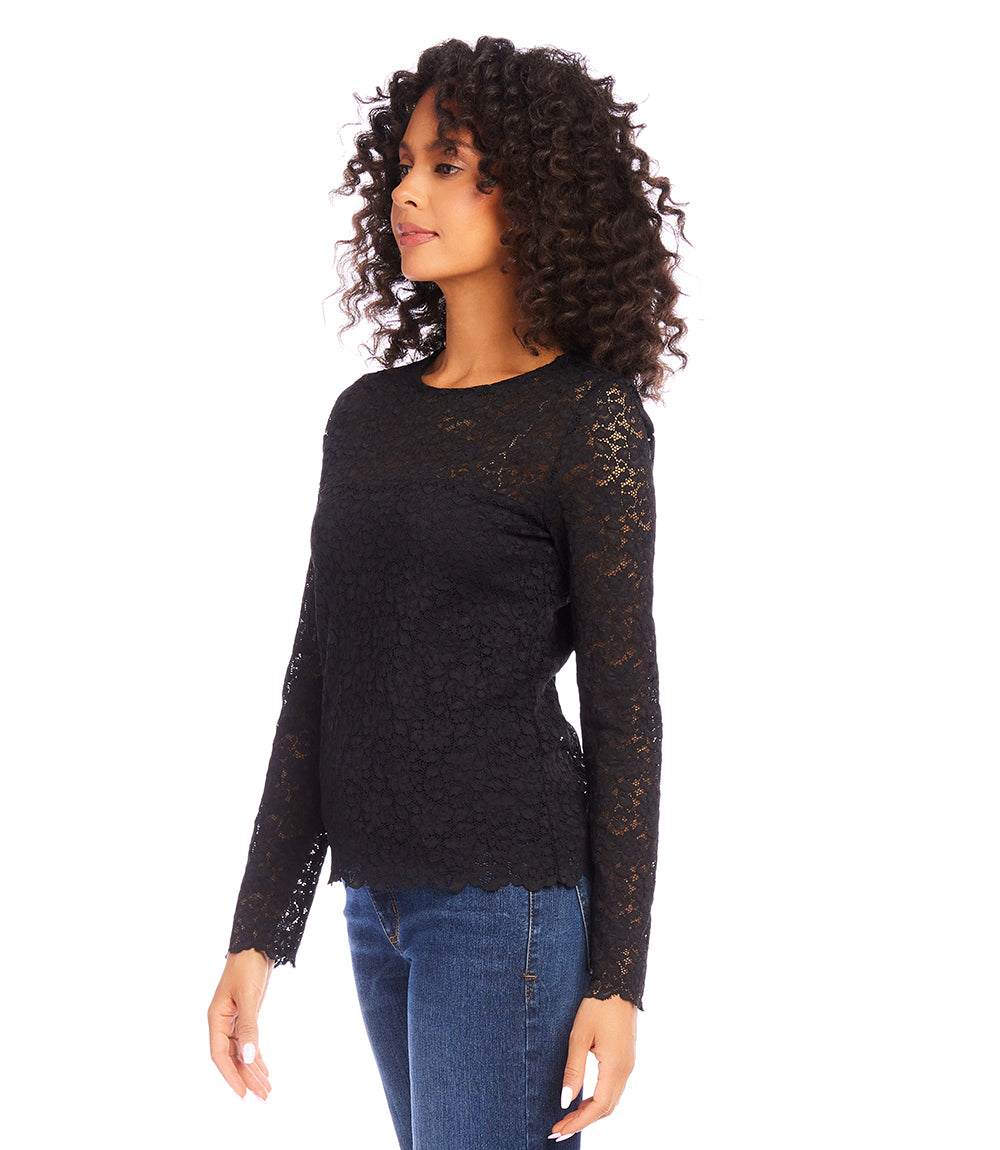 Woman wearing black scalloped lace top with sheer long sleeves and crew neck paired with blue jeans