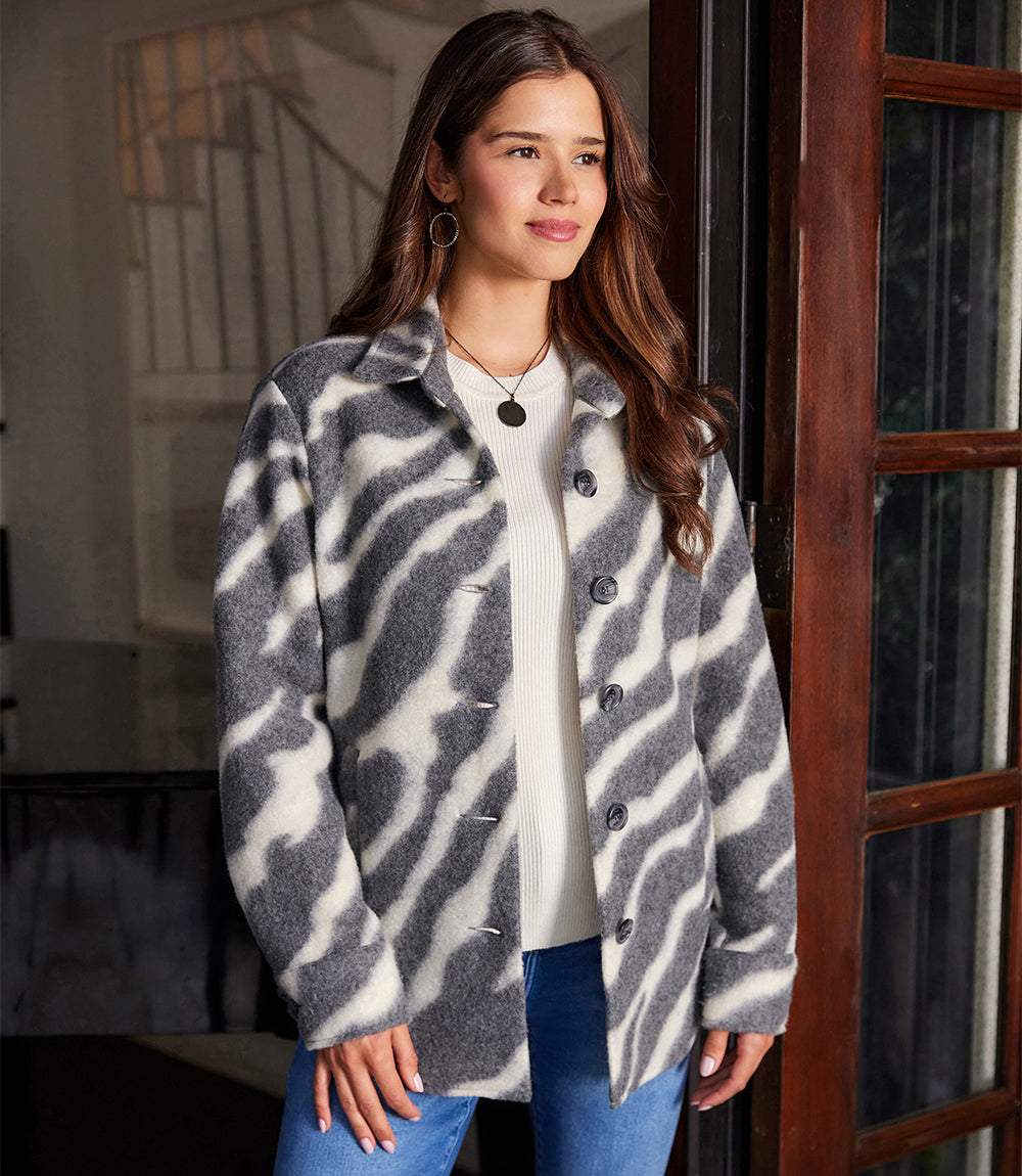 Woman wearing a loose-fit brushed shirt jacket with bold zebra print made from a wool blend, featuring a button front, collar, and welt pockets.