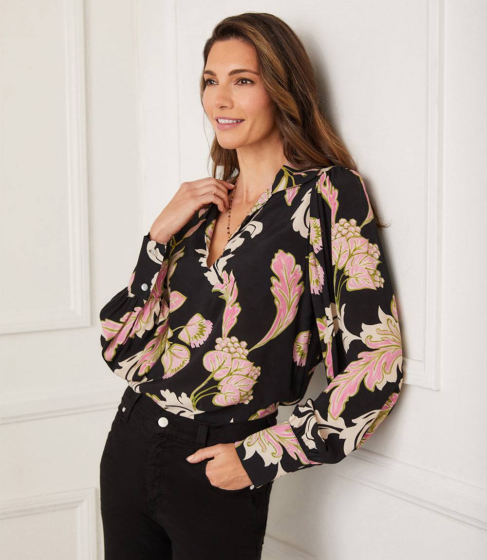 Woman wearing a black Blouson V-Neck Top with pink and beige chalk floral print and blouson sleeves.