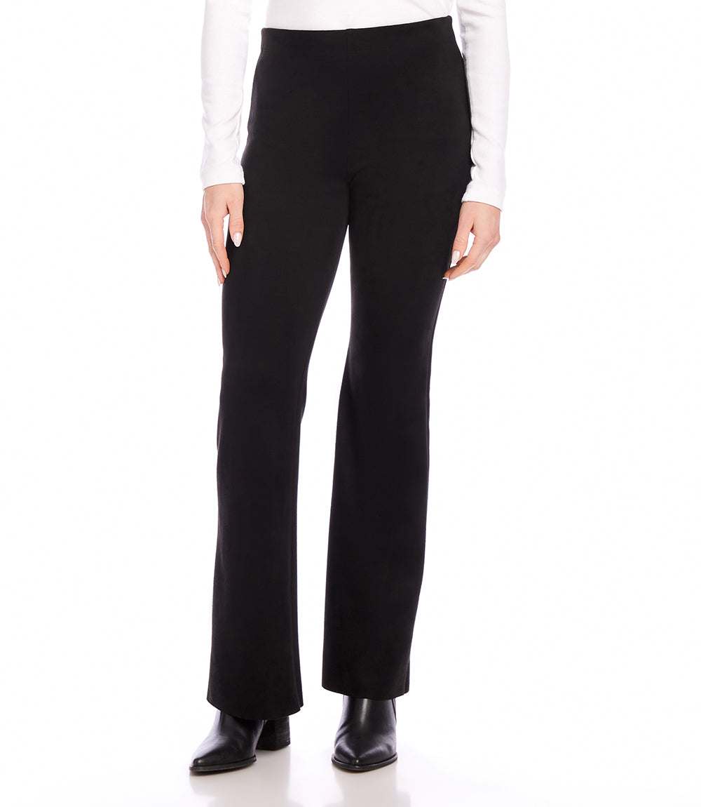 Black faux suede bootcut pants with raw edge hem and high-rise fit modeled with black boots and white long-sleeve top