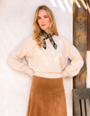 woman wearing tan sweater with green scarf