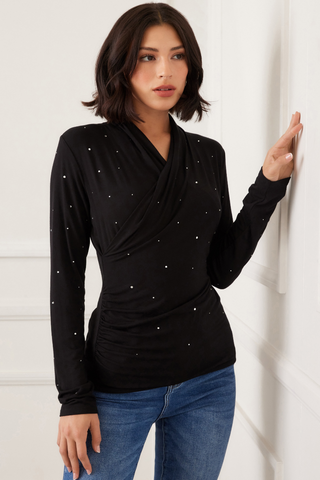 Woman wearing a black long-sleeve top with silver embellishments against a white background