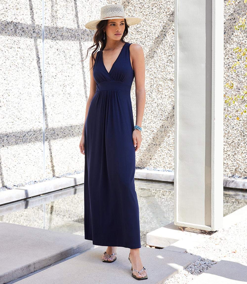 Woman wearing navy blue V-neck maxi dress with empire waist and sleeveless design outdoors