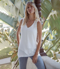 Woman wearing white layered tank with V-neck and asymmetric hem outdoors