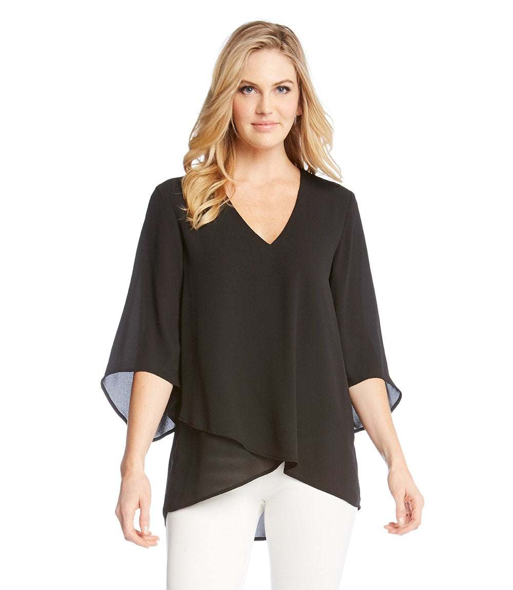 Woman wearing black bracelet sleeve asymmetric top with V-neck and layered hem paired with white pants