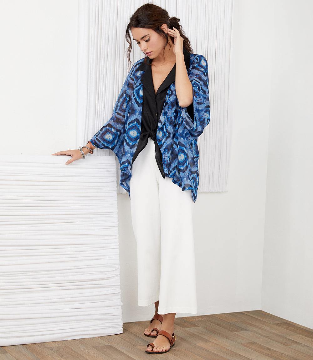 Woman wearing white Brooklyn Cropped Pants with elastic waistband and wide leg, paired with blue patterned kimono and sandals