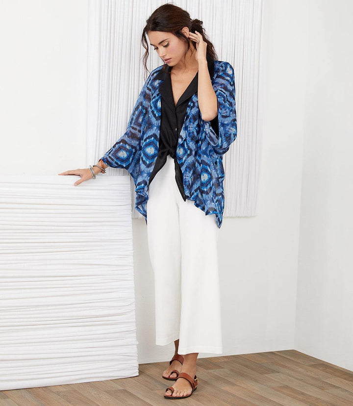 Woman wearing white Brooklyn Cropped Pants with elastic waistband and wide leg, paired with blue patterned kimono and sandals
