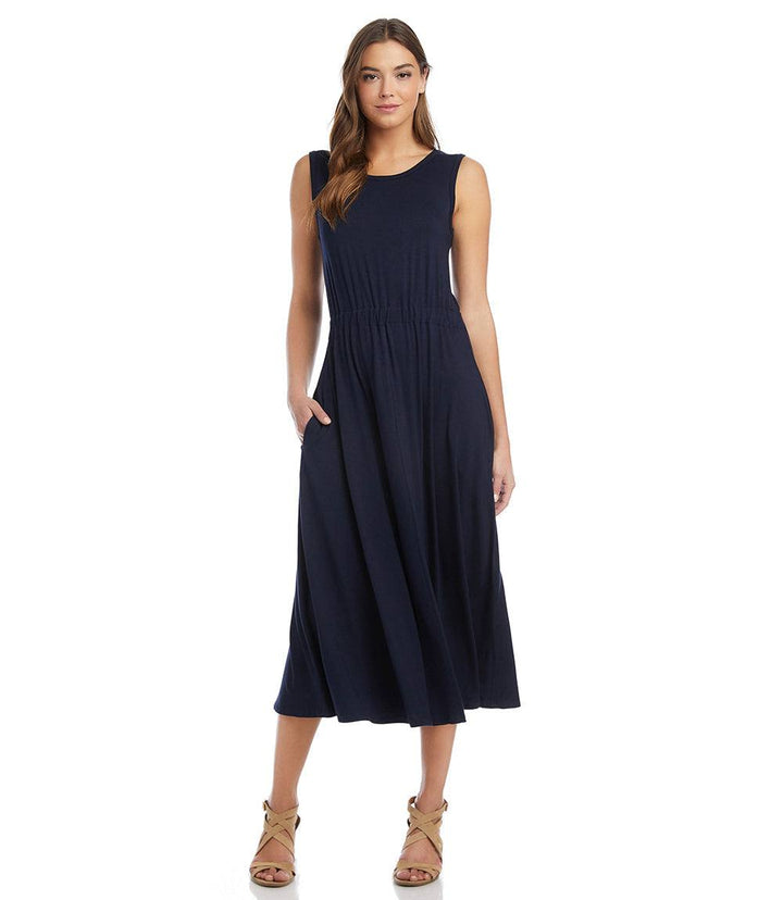 Woman wearing a navy sleeveless artisan dress with elasticized waistband and pockets