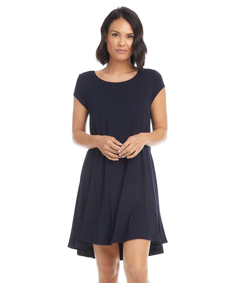 Woman wearing a navy Maggie Trapeze Dress with cap sleeves, boat neckline, and high-low hem made from stretch-jersey knit.