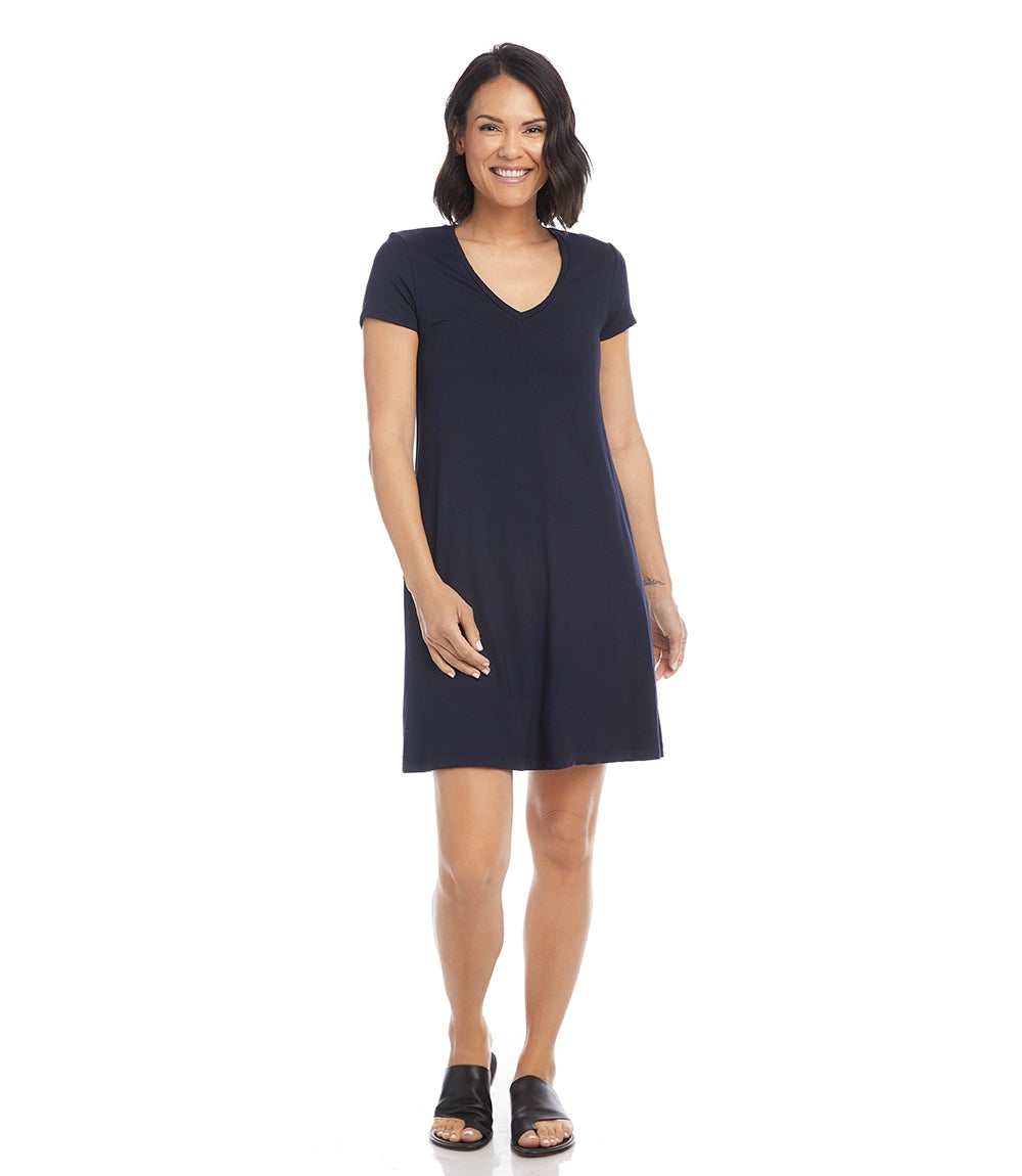 Woman wearing a navy Quinn V-Neck Pocket Dress with short sleeves and side pockets, standing and smiling